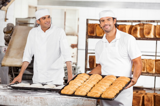 Smiling Baker Showing Breads In Baking Tray By Colleague - Foto, immagini