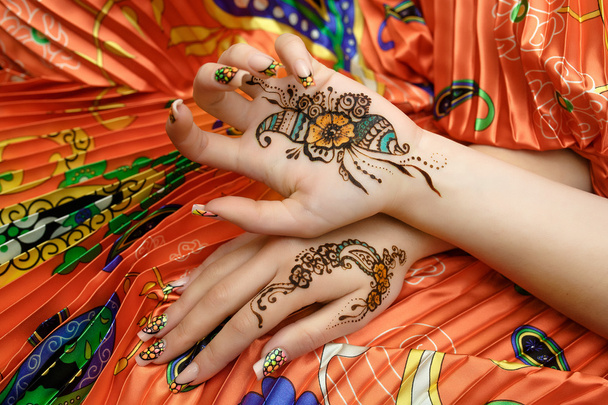 Two womans hands mehendi picture orange bright fabric with pleats - 写真・画像