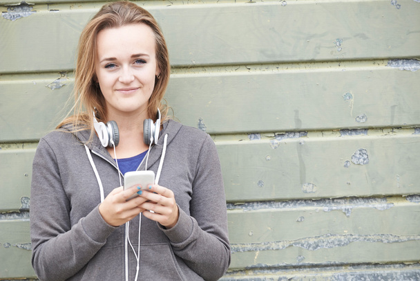 Teenage Girl Wearing Headphones And Listening To Music In Urban  - Foto, afbeelding