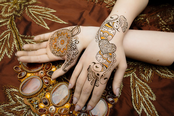 Two womans hands mehendi picture orange bright fabric with pleats - Foto, immagini