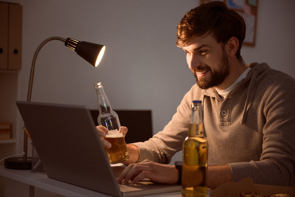 Man using laptop and having a beverage - Foto, afbeelding