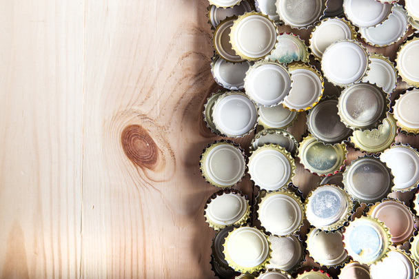 caps of beer on a wooden board, top view - Fotó, kép