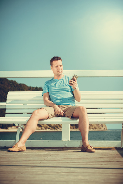 Man tourist on pier using smartphone. Technology. - 写真・画像
