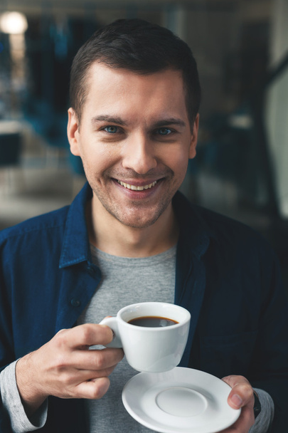 Attractive young guy is enjoying hot drink - Fotografie, Obrázek