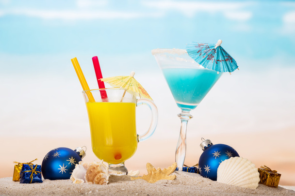 SAP, cocktail, zeester, kerstballen, giften in zand tegen zee. - Foto, afbeelding