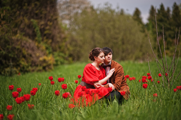 Pár átölelve szerelmes piros tulipán területén. Stílusos férfi bársonyos - Fotó, kép