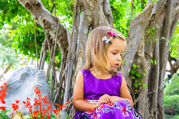 little girl in a tropical garden. bonsai tree - Foto, Imagen