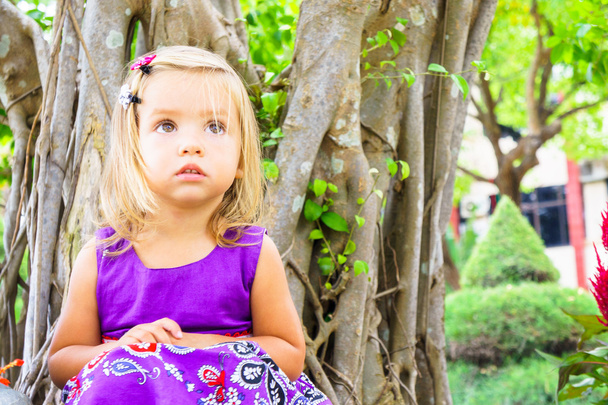 little girl in a tropical garden. bonsai tree - Photo, Image