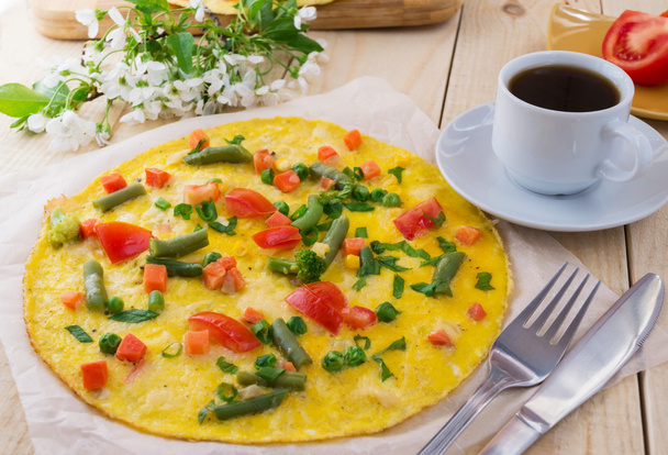 Omelette com legumes em um fundo de madeira, e uma xícara de café.Café da manhã
 - Foto, Imagem