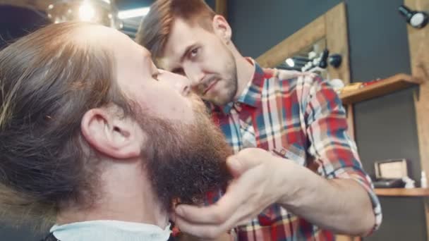 Peluquero esparciendo aceite en la barba del hombre
 - Metraje, vídeo