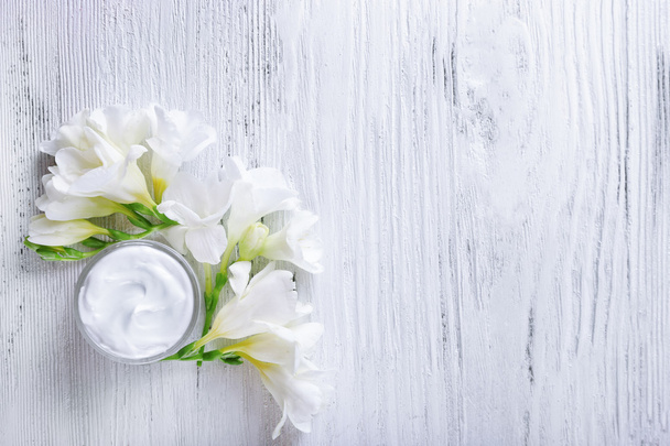 Hydraterende crème en bloemen op wit - Foto, afbeelding