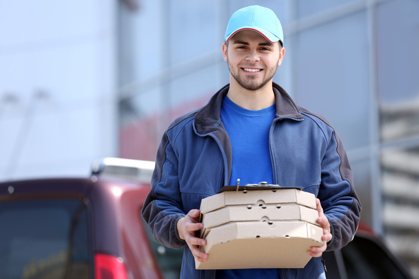 чоловік тримає піцу зовні
 - Фото, зображення