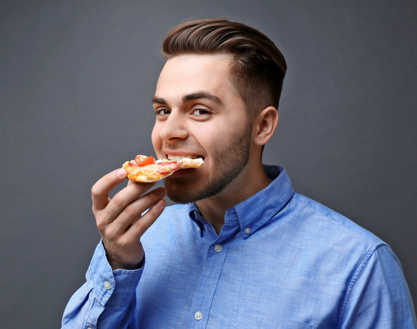 Young handsome man eating pizza   - Valokuva, kuva