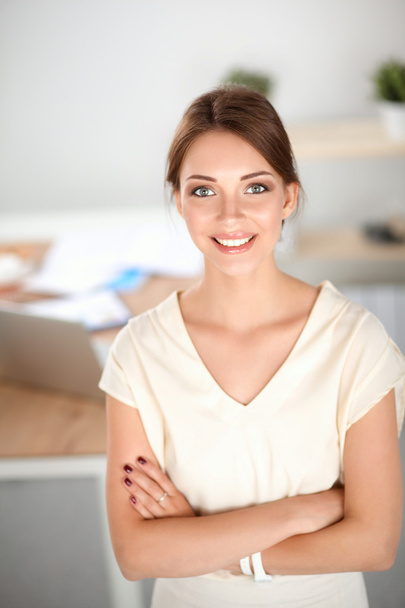 Attractive businesswoman standing near wall in office - Photo, image