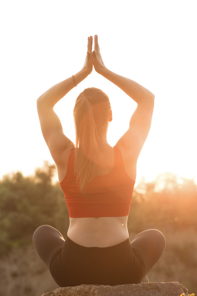 Sporty woman practicing yoga at sunset - Foto, afbeelding