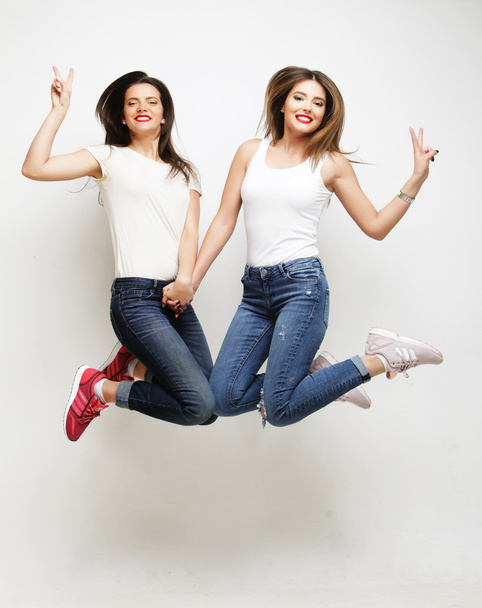 lifestyle portrait of two young hipster girls best friends jump - Фото, зображення