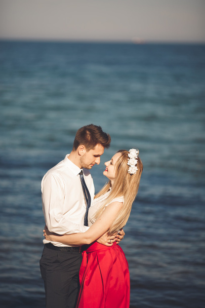 Young happy couple walking on beach smiling holding around each other. Love story - Фото, зображення