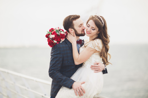 Married wedding couple standing on a wharf over the sea - Foto, imagen