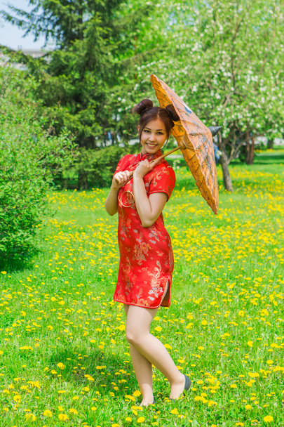 Beautiful asian girl in traditional chinese red dress with bamboo umbrella. - Fotó, kép
