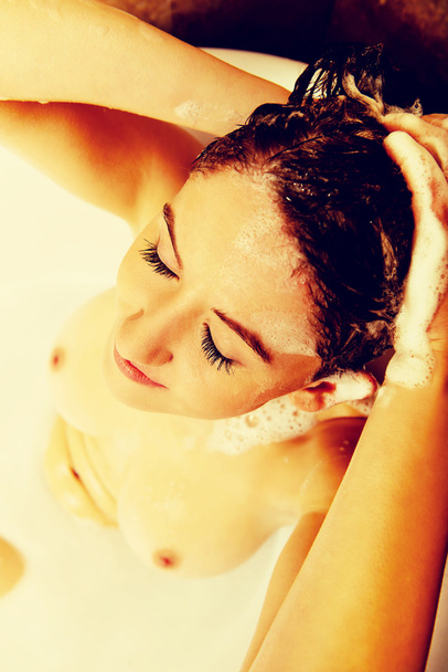 Young topless woman washing hair in bath - Foto, imagen