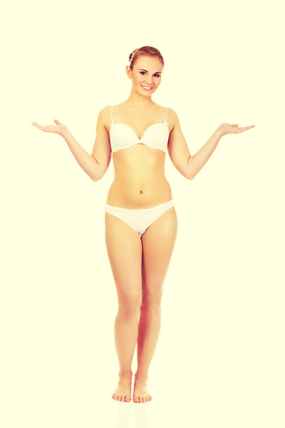 Happy woman in white lingerie presenting something on open palm - Фото, изображение