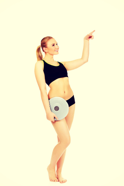 Young athletic woman holding balance board and pointing for something - Fotoğraf, Görsel