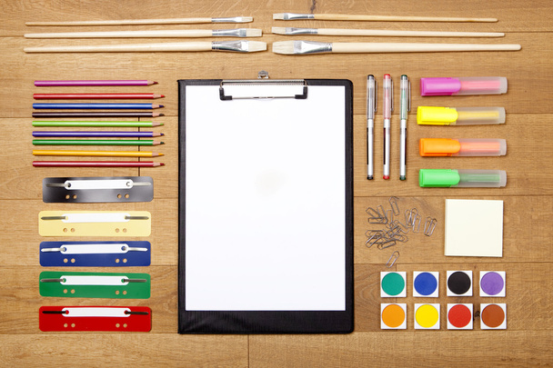 colorful office supplies on wooden flooring, aerial view, with clipboard on empty white paper - Photo, Image