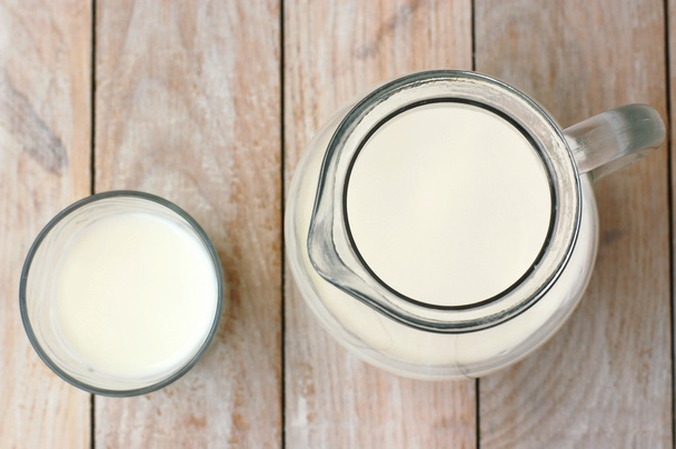 Белое молоко в стакане с кувшином на деревянном фоне
 - Фото, изображение
