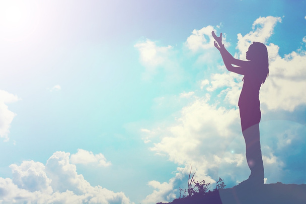 Sylwetka kobiety modlącej się nad pięknym tle nieba - Zdjęcie, obraz