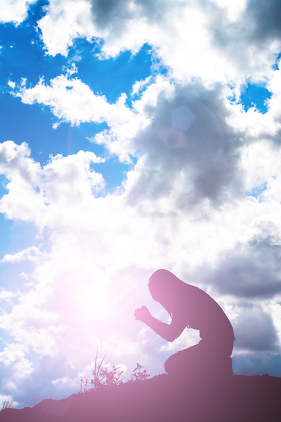 Silhouette di donna che prega su uno sfondo bellissimo cielo - Foto, immagini