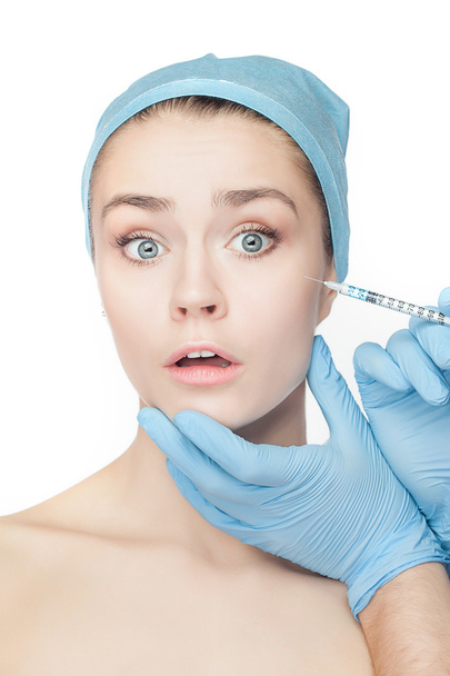 Aantrekkelijke vrouw op plastische chirurgie met spuit in haar gezicht - Foto, afbeelding