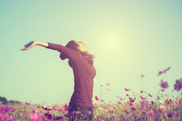 Щастя жінка залишається на відкритому повітрі в квітковому саду під сонячним світлом
 - Фото, зображення