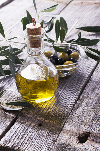 Jug with extra virgin olive oil on cutting board surrounded by branches - Photo, Image
