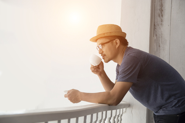 Young hipster man resting at home balcony with the sunrise - Foto, Imagen