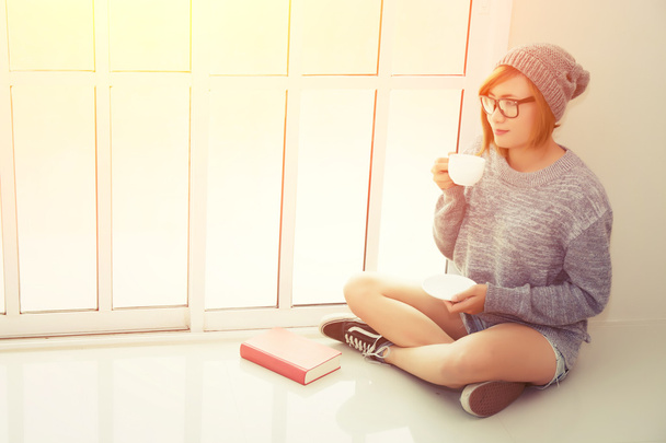 Mooie jonge vrouw drinken koffie in de slaapkamer in de buurt van wi - Foto, afbeelding
