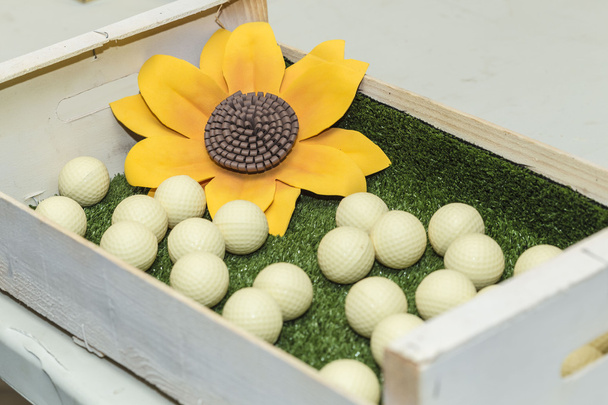 Fleurs jaunes et balles de golf blanches sur une boîte
 - Photo, image