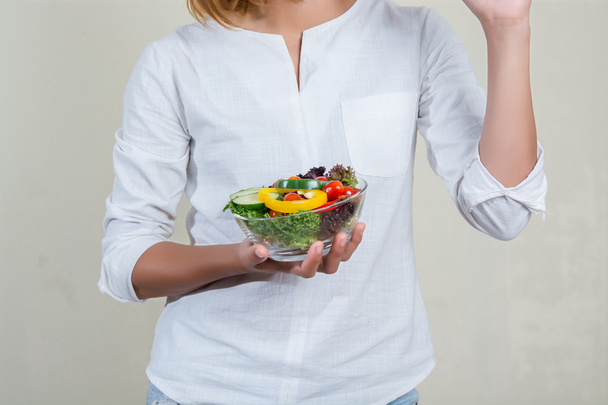 hands of beautiful woman holding big bowl of fresh veggie salad  - Foto, Imagen
