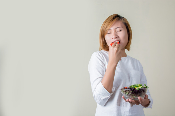 hermosa mujer de pie sosteniendo tazón de ensalada comiendo un poco de vegeta
 - Foto, imagen