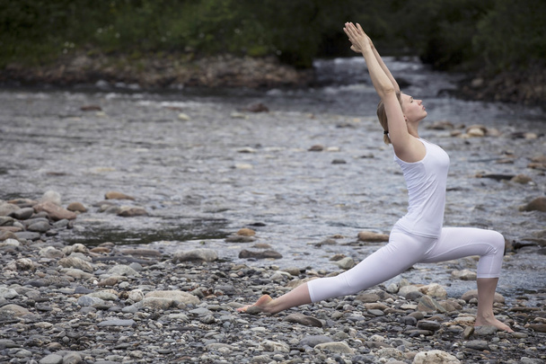 Young woman is practicing yoga at stone shore river - Fotografie, Obrázek