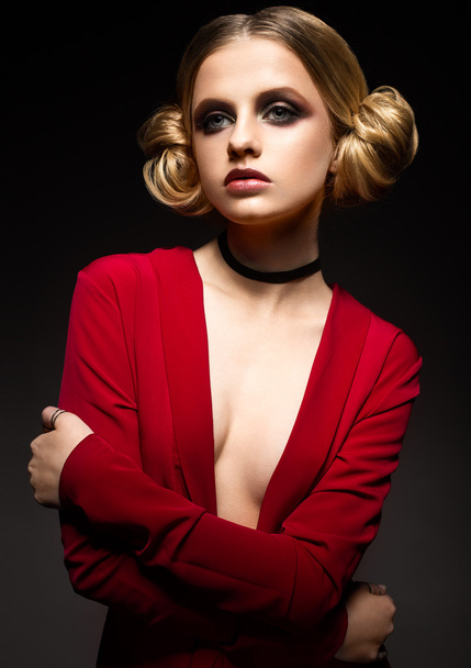 Beautiful girl in a red dress with a deep neckline and black rings on his fingers. The model with bright makeup. - Foto, afbeelding