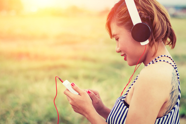 mooie sexy vrouw met blauwe jurk staande luisteren muziek in - Foto, afbeelding