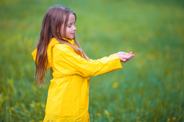 Adorable jeune fille portant un manteau imperméable jouant à l'extérieur par jour pluvieux et ensoleillé
 - Photo, image