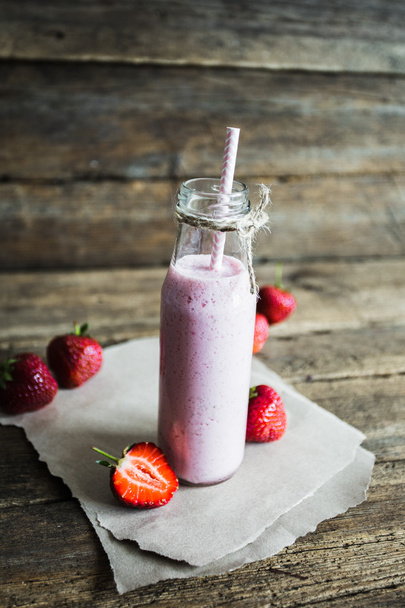 glass of strawberry smoothie and fresh strawberries on a wooden background - Foto, imagen