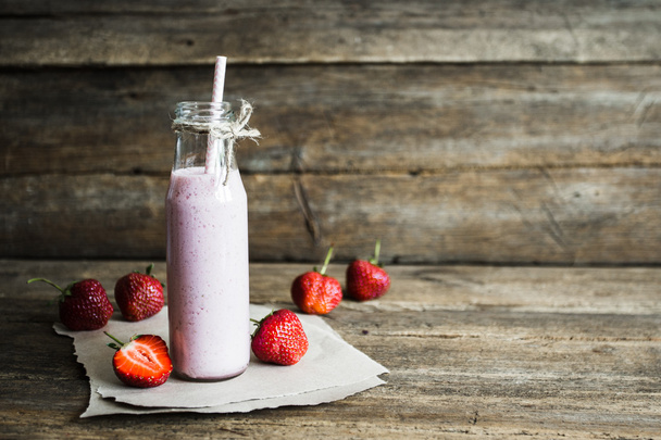 glass of strawberry smoothie and fresh strawberries on a wooden background - Photo, Image