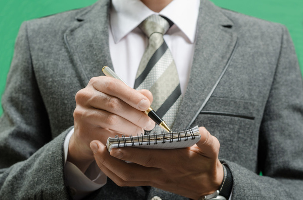 бизнесмен в костюме кладет данные в блокнот
 - Фото, изображение
