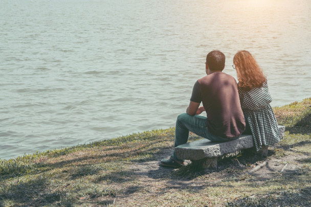 Молода пара сидить біля озера в парку
 - Фото, зображення