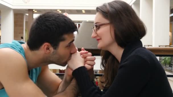 Ευτυχισμένο ζευγάρι κρατώντας και αγγίζει κάθε άλλα χέρια σε καφετέρια στο εμπορικό κέντρο και φιλιά - Πλάνα, βίντεο