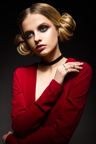 Beautiful girl in a red dress with a deep neckline and black rings on his fingers. The model with bright makeup. - 写真・画像