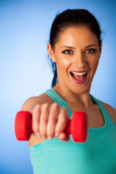 active woman with dumbbells workout in fitness gym over blue bac - Photo, image