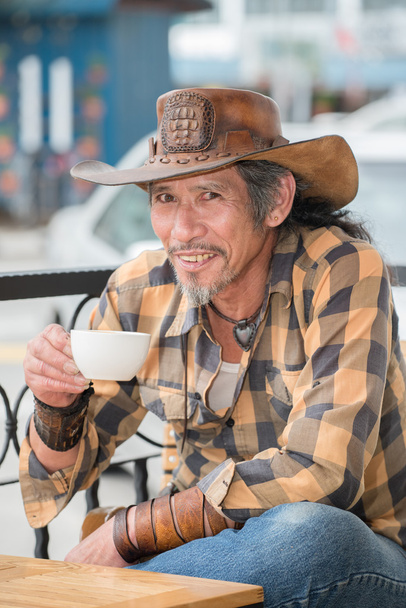 Asian cowboy with a Cup of coffee - Фото, изображение